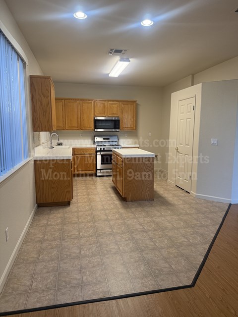 A kitchen with wooden cabinets and a tiled floor.