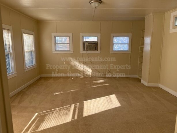 A sunny room with a carpet and three windows.