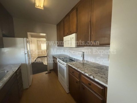A kitchen with wooden cabinets and a marble countertop.