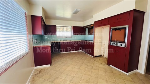 A kitchen area with a red cabinet and a countertop with a microwave and oven.