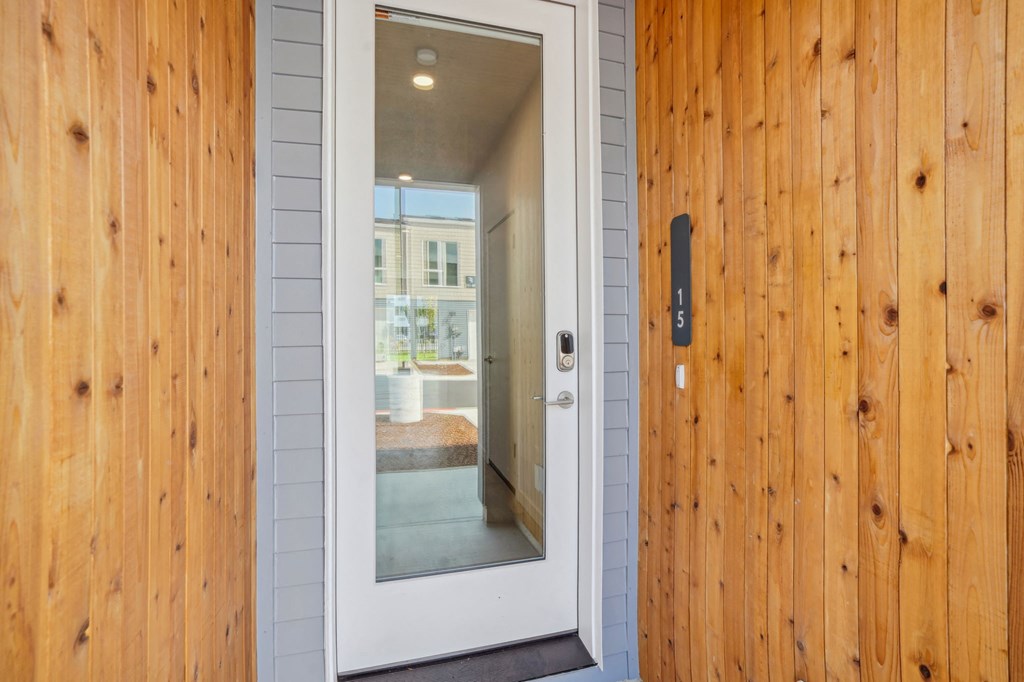 front wooden door with a view of entryway hallway through it
