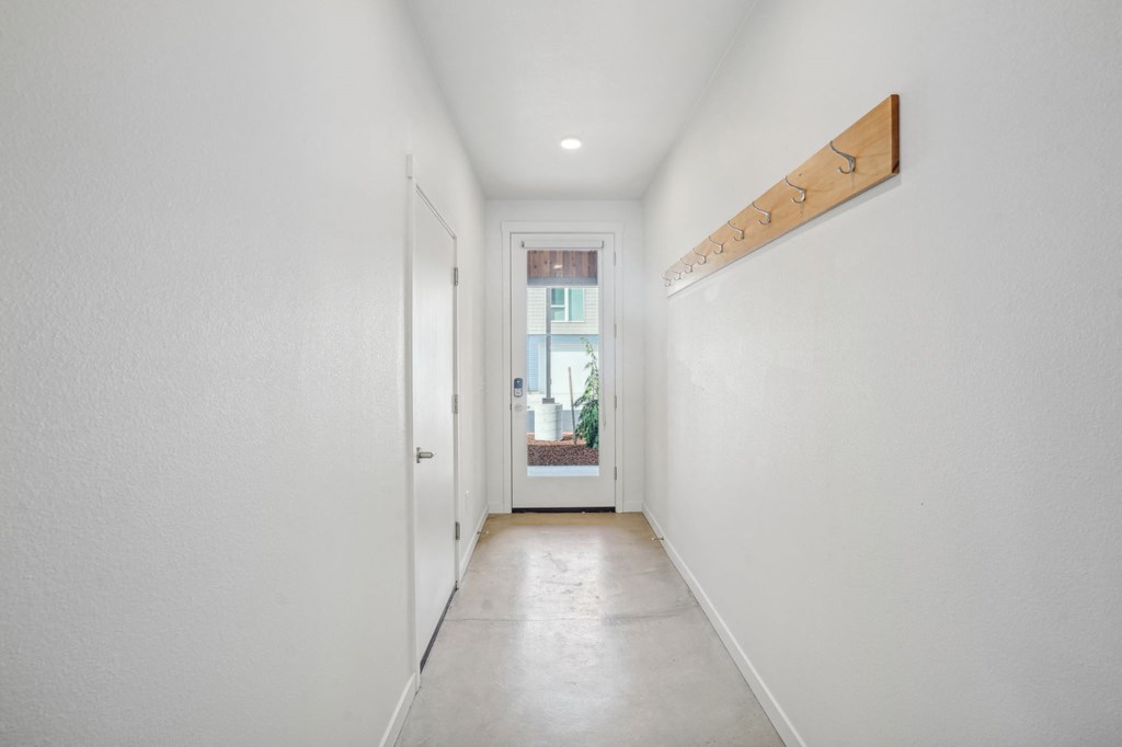 a long hallway with white walls and a white door to a house
