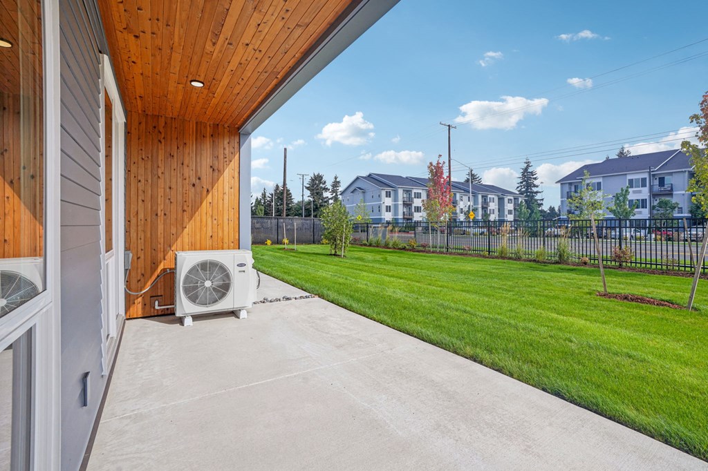 the patio of a home with a yard and an a/c on it