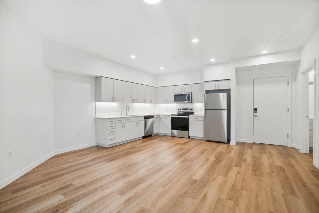 a white kitchen with a hard wood floor and a refrigerator