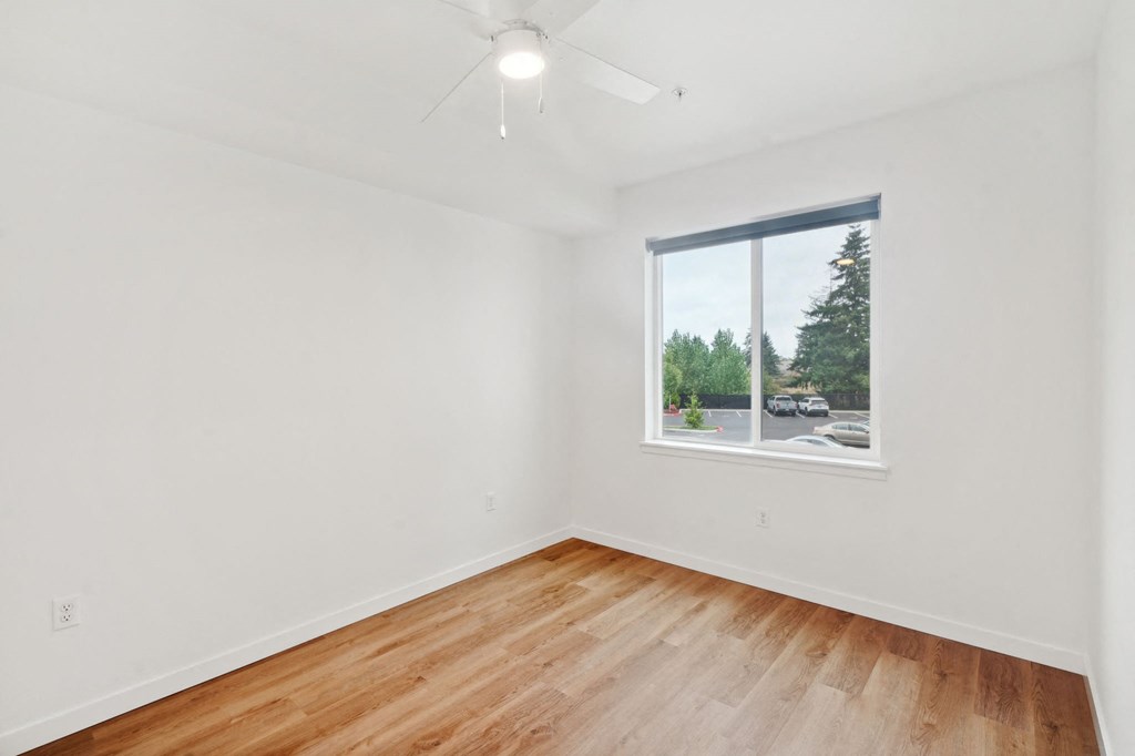 a living room with white walls and a window and wood floors