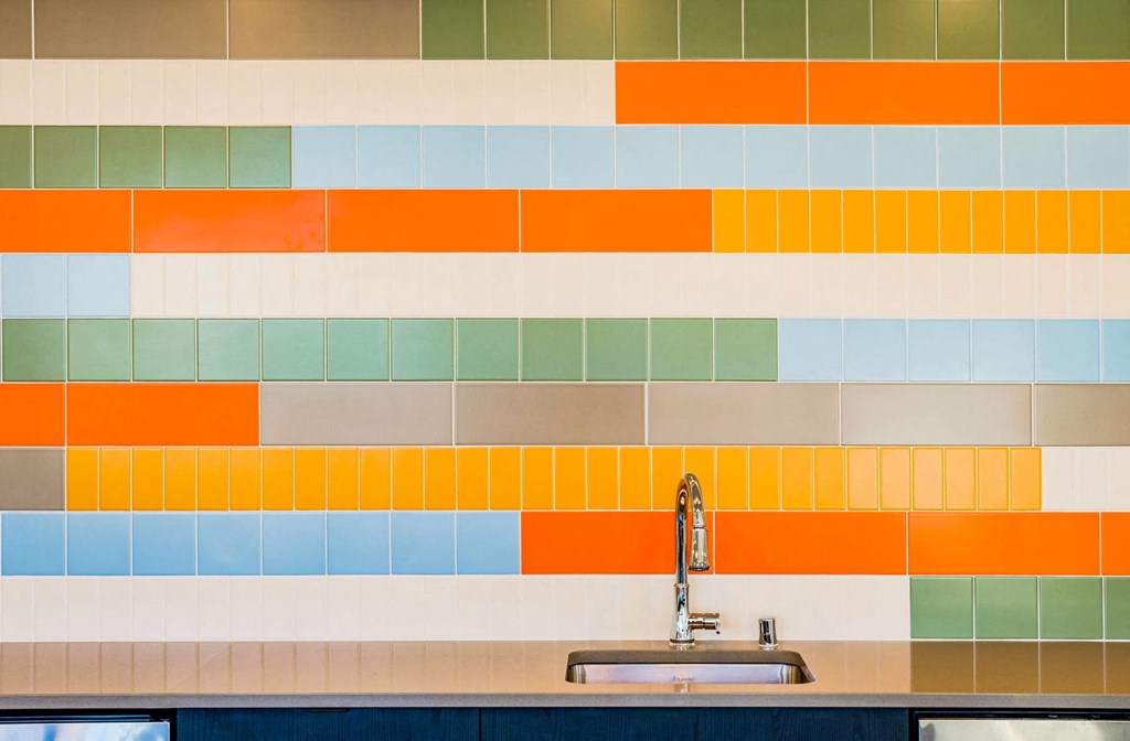 a kitchen with a sink and colorful tiles on the wall