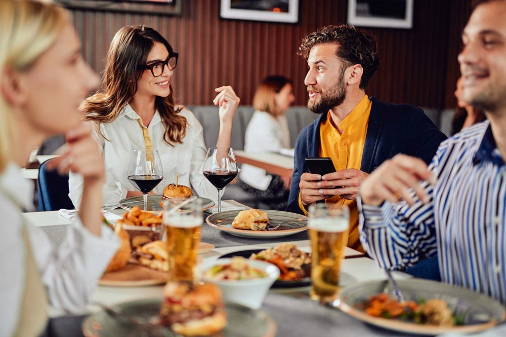 a group of people sitting at a table with food and drinks