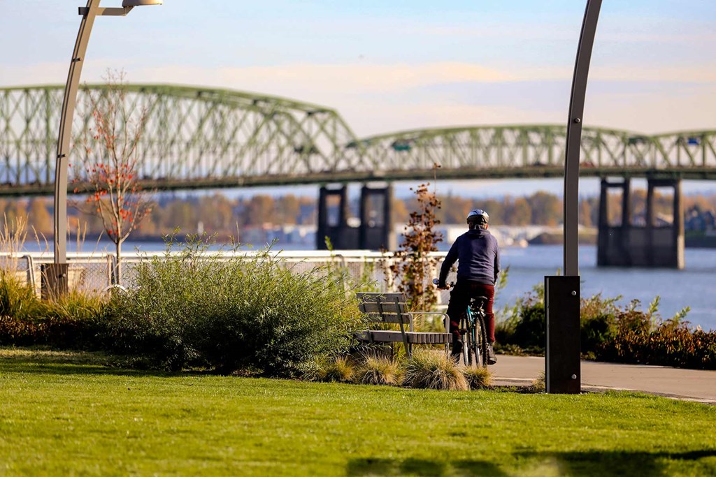 a man riding a bike down a path near a bridge