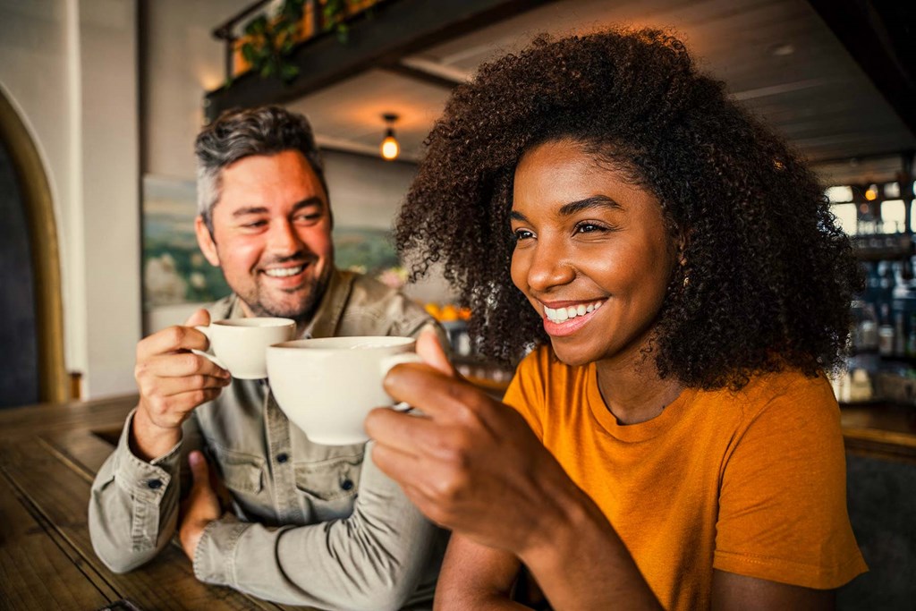 a man and a woman sitting at a table with cups of coffee
