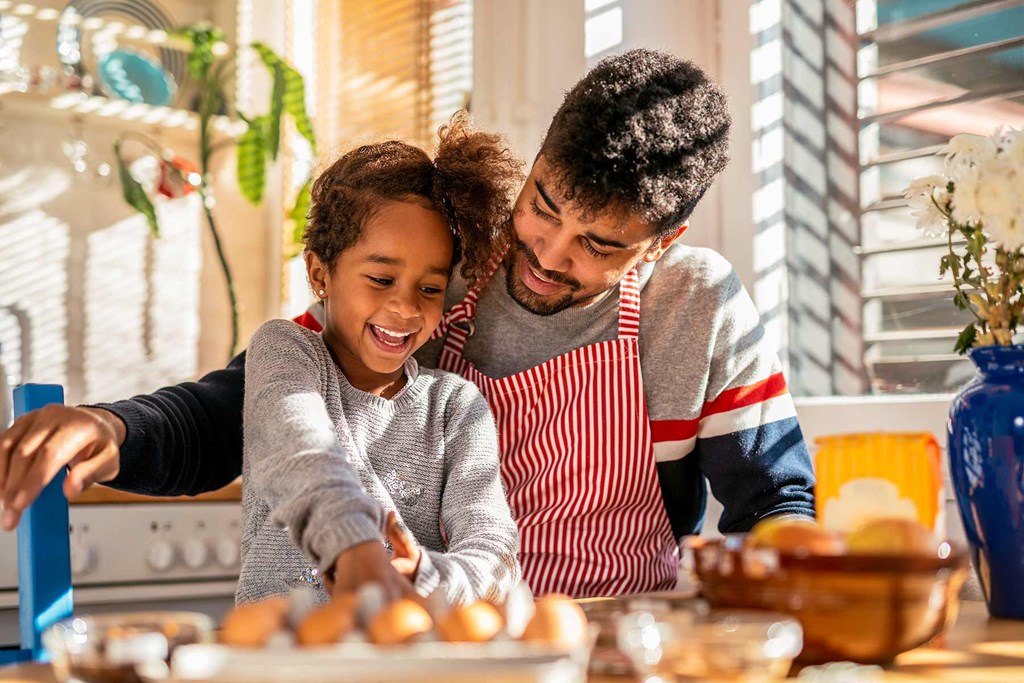 a father and daughter preparing food in the kitchen