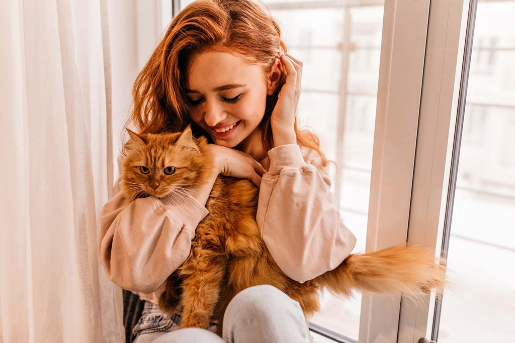 a woman with a cat sitting on a window sill
