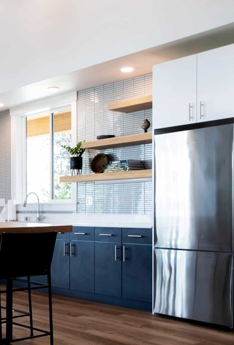 a kitchen with blue cabinets and a stainless steel refrigerator