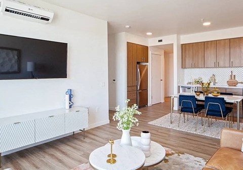 A living room with a white sofa, a television, and a dining area with a table and chairs.