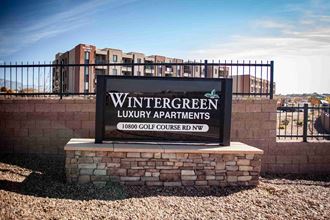 a sign for the wintergreen luxury apartments sign in front of a fence and buildings