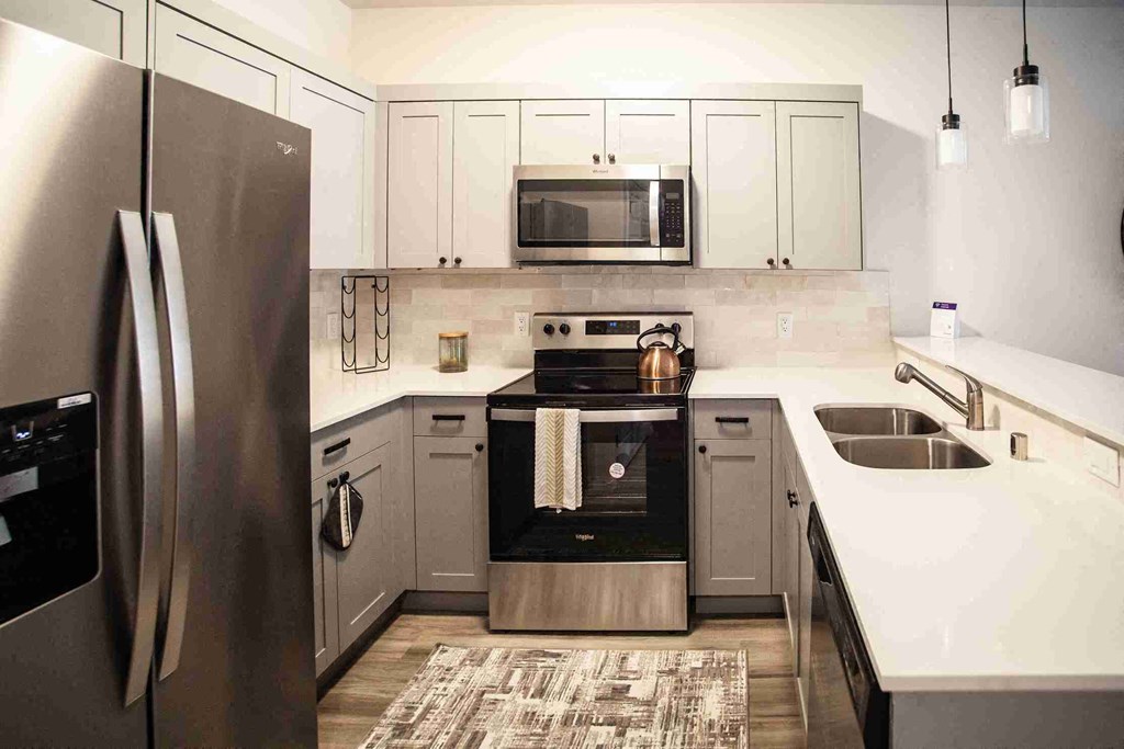 Modern kitchen with a stainless steel refrigerator and a black stove top oven.