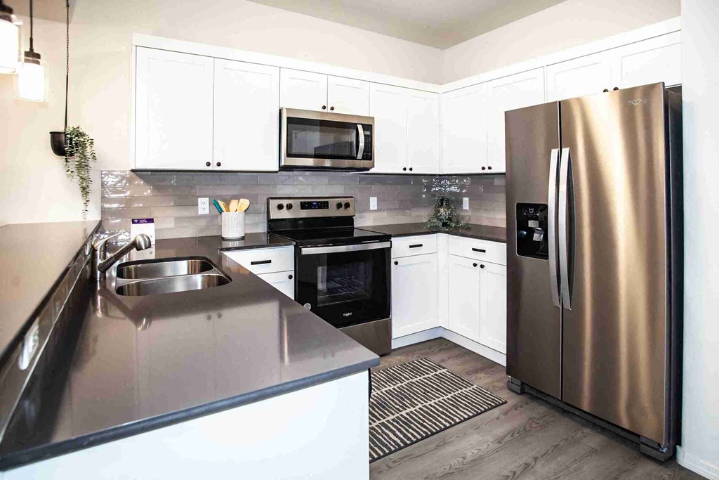 A modern kitchen with a stainless steel refrigerator and white cabinets.
