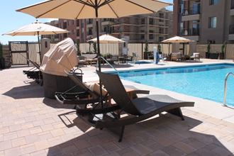 a pool with two lounge chairs and umbrellas at a hotel pool