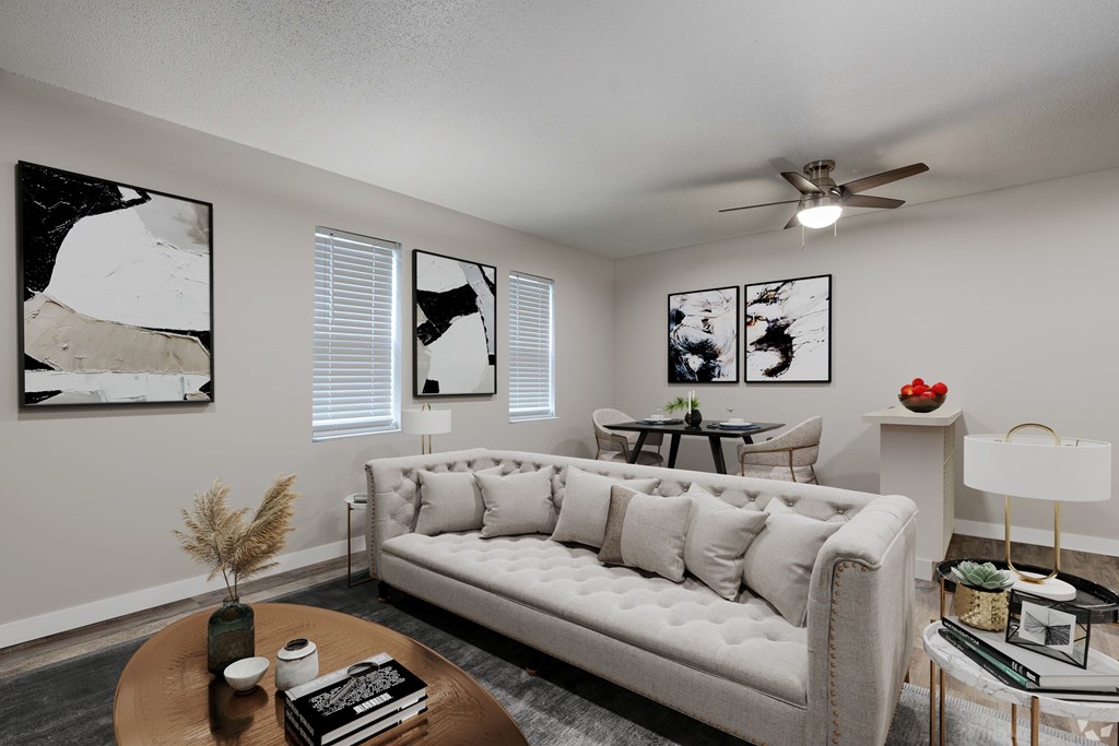 A living room with a white couch, a coffee table, and three framed pictures on the wall.