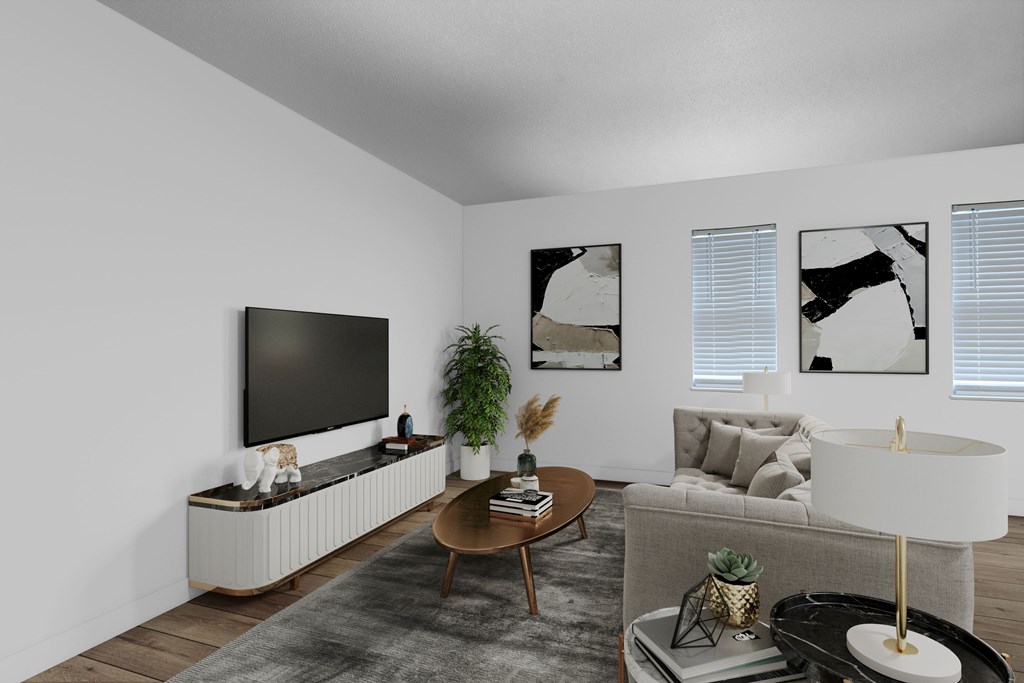 A living room with a grey sofa, a wooden coffee table, a black television, and three framed pictures on the wall.
