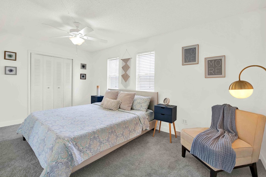 A bedroom with a bed, chair, and pictures on the wall.