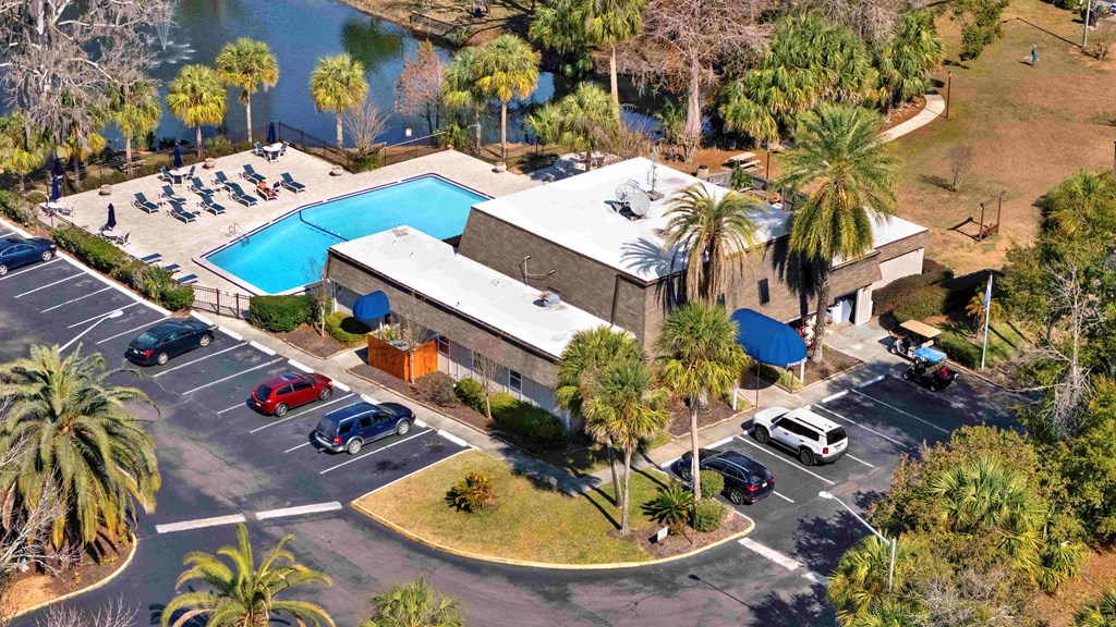 A large building with a pool and a parking lot in front.