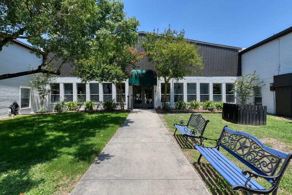 A walkway with two benches and a building in the background.