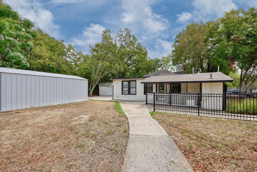 a small house with a yard and a black fence  at Mayfield Gardens, San Antonio, TX, 78211