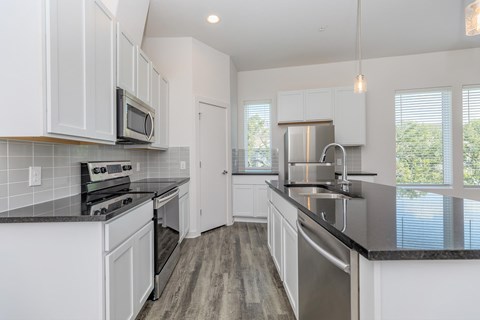 A kitchen with white cabinets and a black countertop.