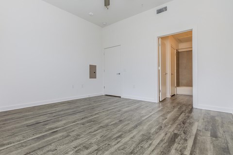 A room with a wooden floor and a white wall with a door.