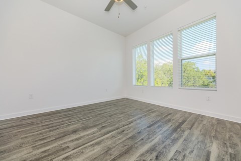 A room with a ceiling fan and wooden flooring.