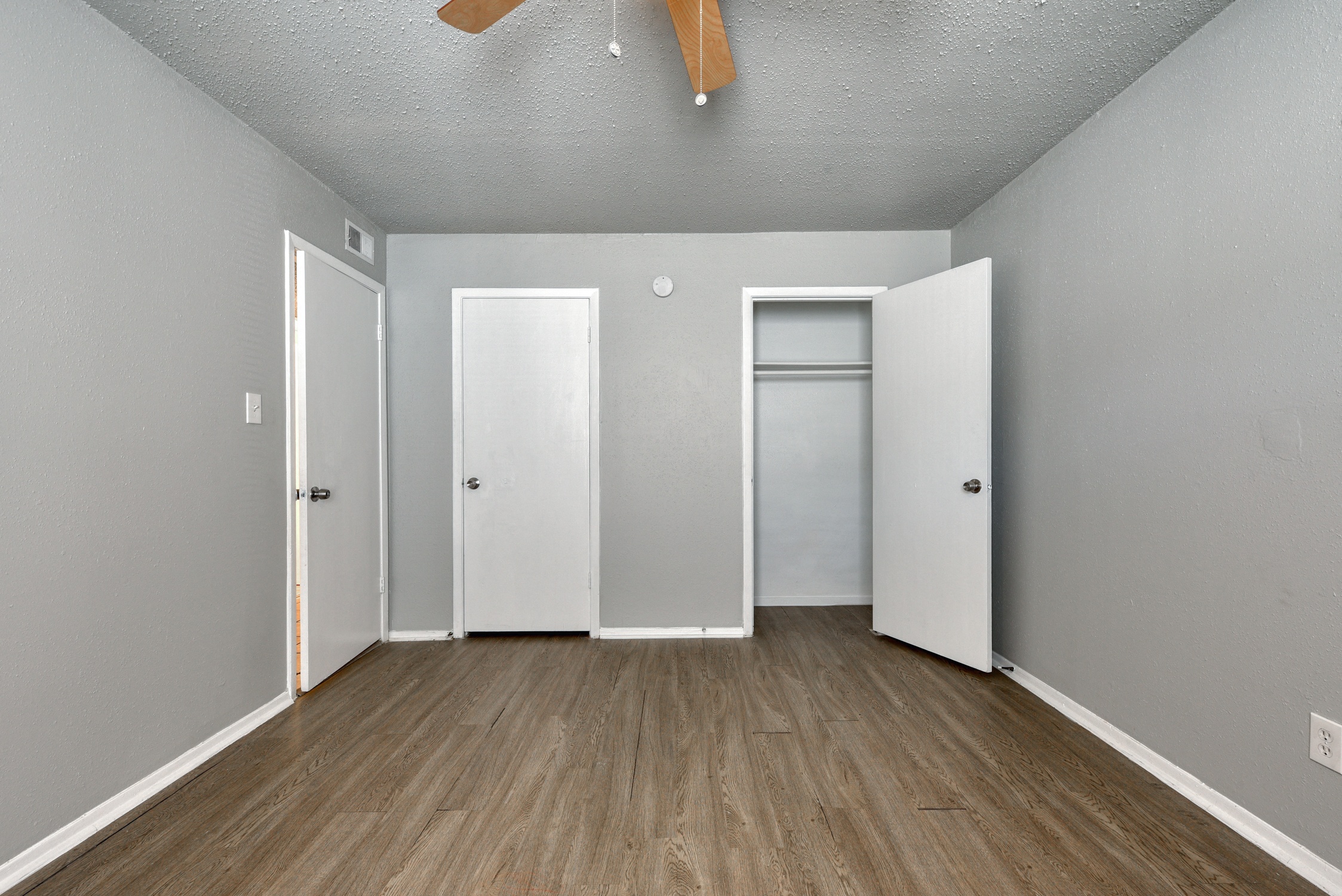 the living room of an apartment with wood floors and white walls