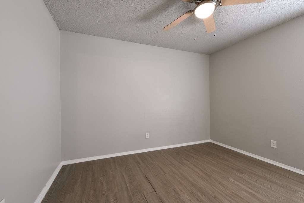 an empty room with wooden floors and a ceiling fan at Eagle View Apartments, Pleasanton, Texas
