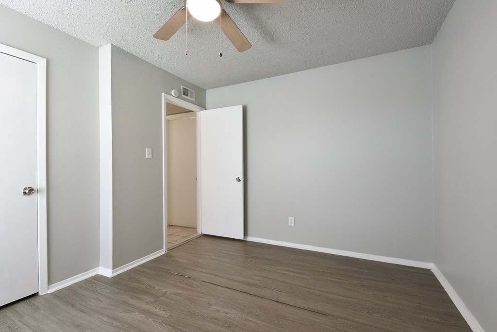 an empty living room with wood floors and a ceiling fan at Eagle View Apartments, Texas