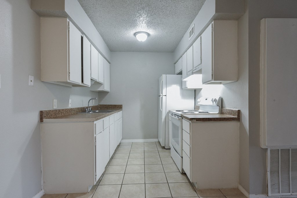 an empty kitchen with white cabinets and a white refrigerator at Eagle View Apartments, Texas