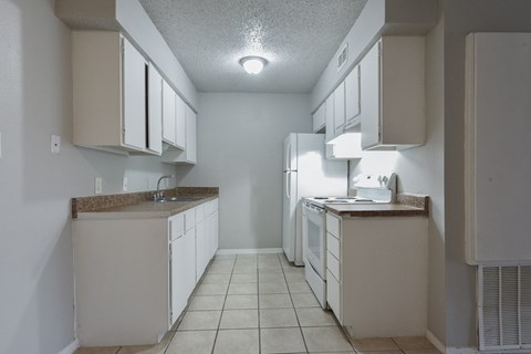 an empty kitchen with white cabinets and a white refrigerator at Eagle View Apartments, Texas