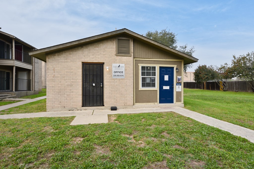 a small tan building with a blue door and a sign on the side of it at Eagle View Apartments, Texas