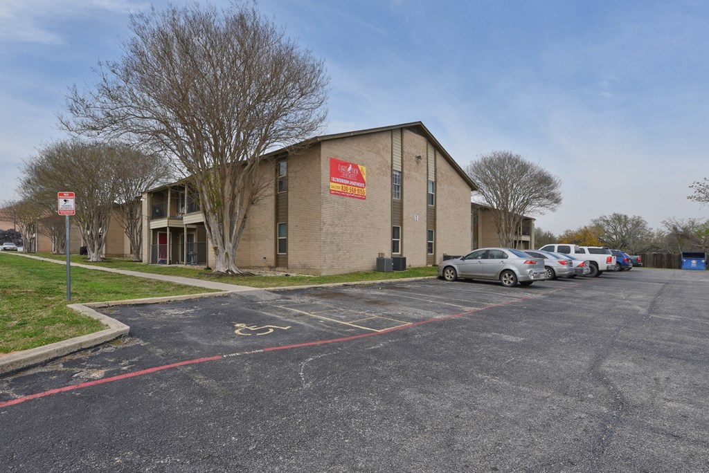 a parking lot in front of a brick building with cars parked outside at Eagle View Apartments, Pleasanton, TX, 78064