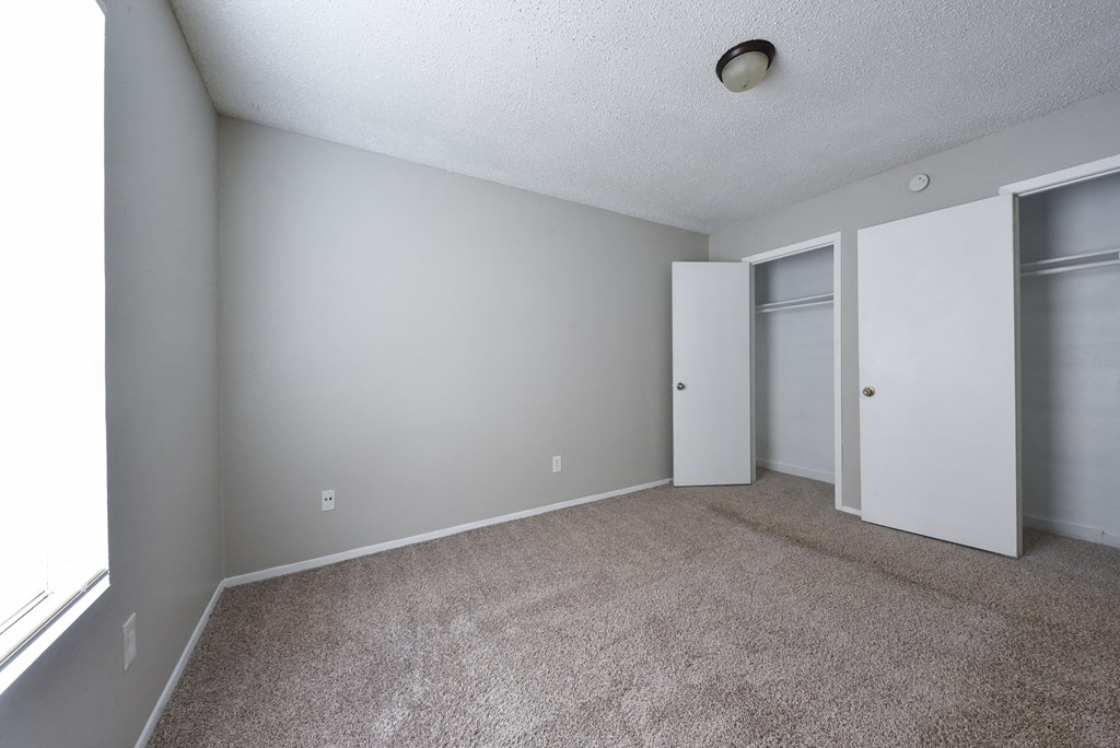 an empty living room with carpet and a door to a closet at Eagle View Apartments, Pleasanton