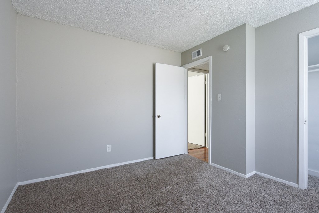 an empty room with carpet and a door to a hallway at Eagle View Apartments, Pleasanton, TX