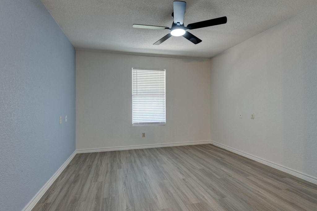 A room with a ceiling fan and a window with blinds.