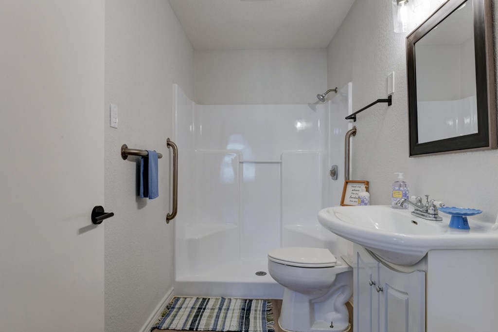A white bathroom with a toilet, sink, and shower.
