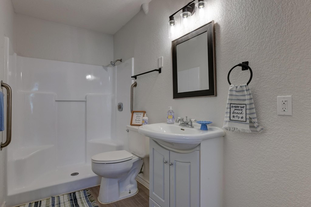 A white bathroom with a toilet, sink, and shower.