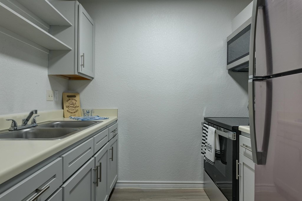 A kitchen with a sink, stove, and refrigerator.