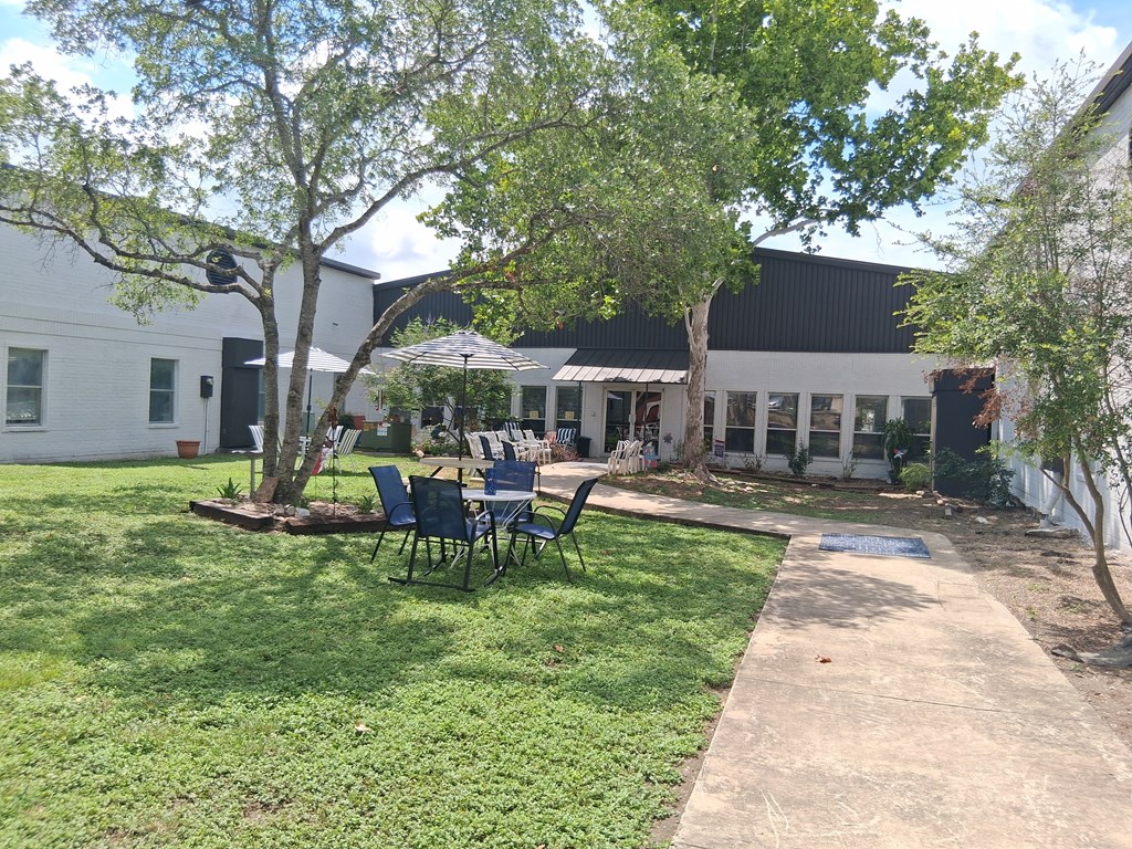 A white building with a black roof and a green lawn in front.