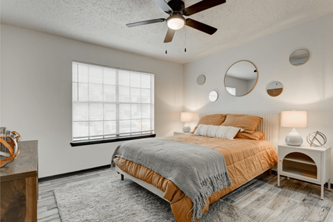 A bedroom with a bed, a ceiling fan, and a window with blinds at Ranch at 1856 Apartments, San Marcos, TX, 78666