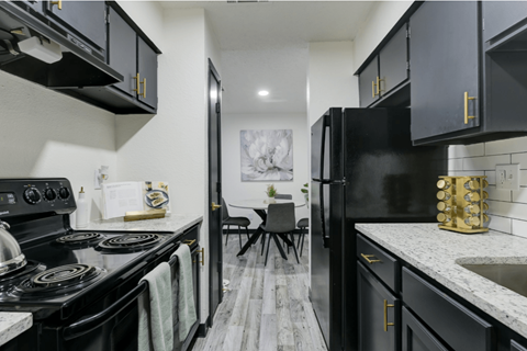A kitchen with black cabinets and a white stove top oven at Ranch at 1856 Apartments, San Marcos, Texas, 78666
