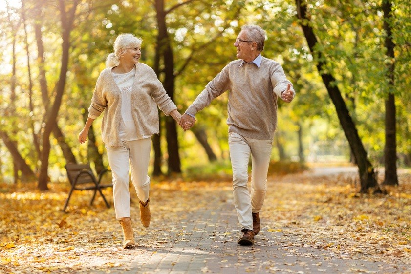An elderly couple holding hands and walking in a park at Silver Oaks Villas Apartments, Texas, 78130