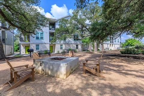 A backyard with a fire pit and chairs.