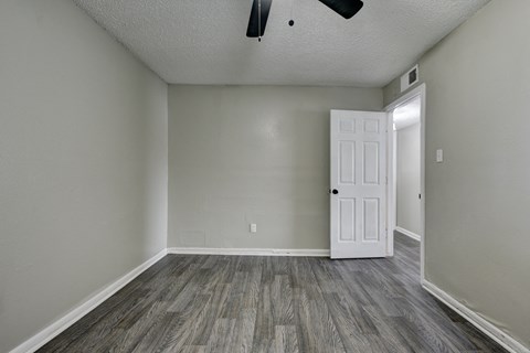 an empty living room with wood flooring and a white door at The Crossings at Montrose Apartments, San Antonio, Texas