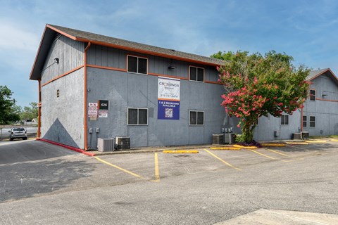 a large building with a parking lot and a tree at The Crossings at Montrose Apartments, San Antonio, 78223